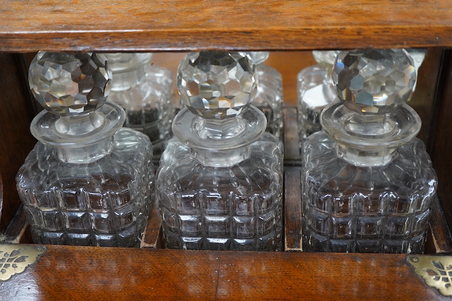 A Victorian oak three-bottle tantalus, with compartment for glasses, 30cm high x 34cm wide
